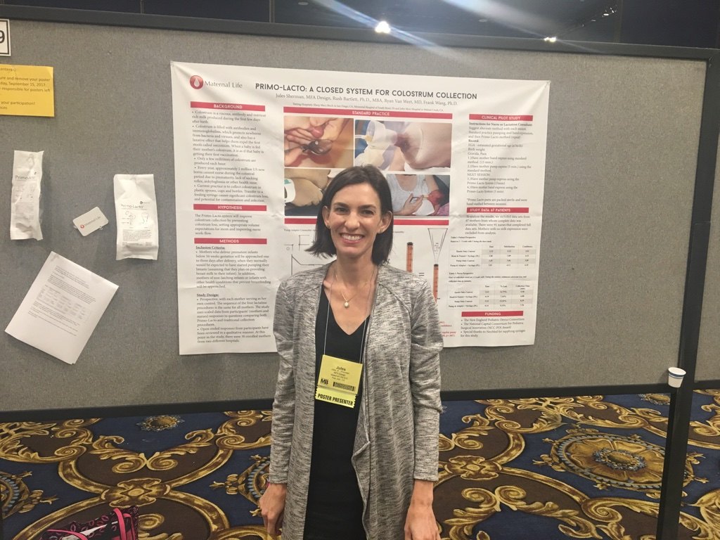 Jules Sherman, wearing a Poster Presenter badge, in front of the poster Primo-Lacto: A Closed System for Colostrum Collection.