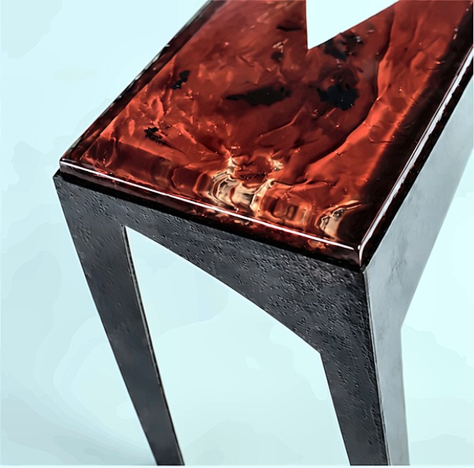 A close view of one corner of the console table, showing the swirled deep red finish on the top and a dark textured leg.