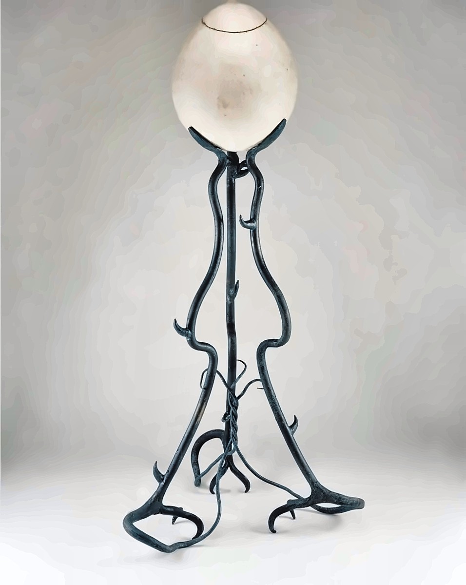 A floor lamp with a large white egg-shaped shade held up by a dark iron stand of twisting, branch-like legs.